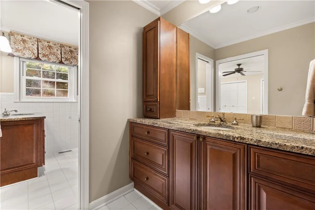 Bathroom with vanity, light tile patterned floors, crown molding, tile walls, and a ceiling fan