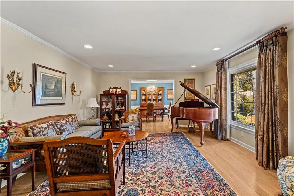 Living area with light wood-style floors, a chandelier, crown molding, and recessed lighting