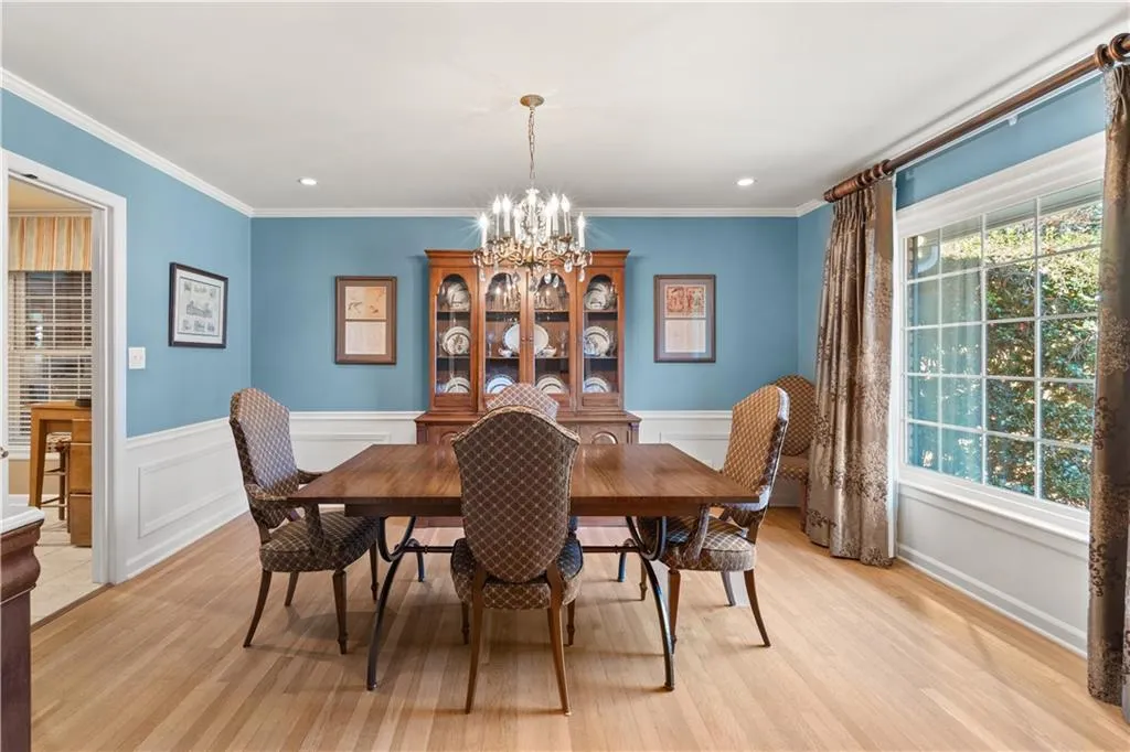 Dining area featuring a chandelier, light wood-style flooring, ornamental molding, wainscoting, and recessed lighting