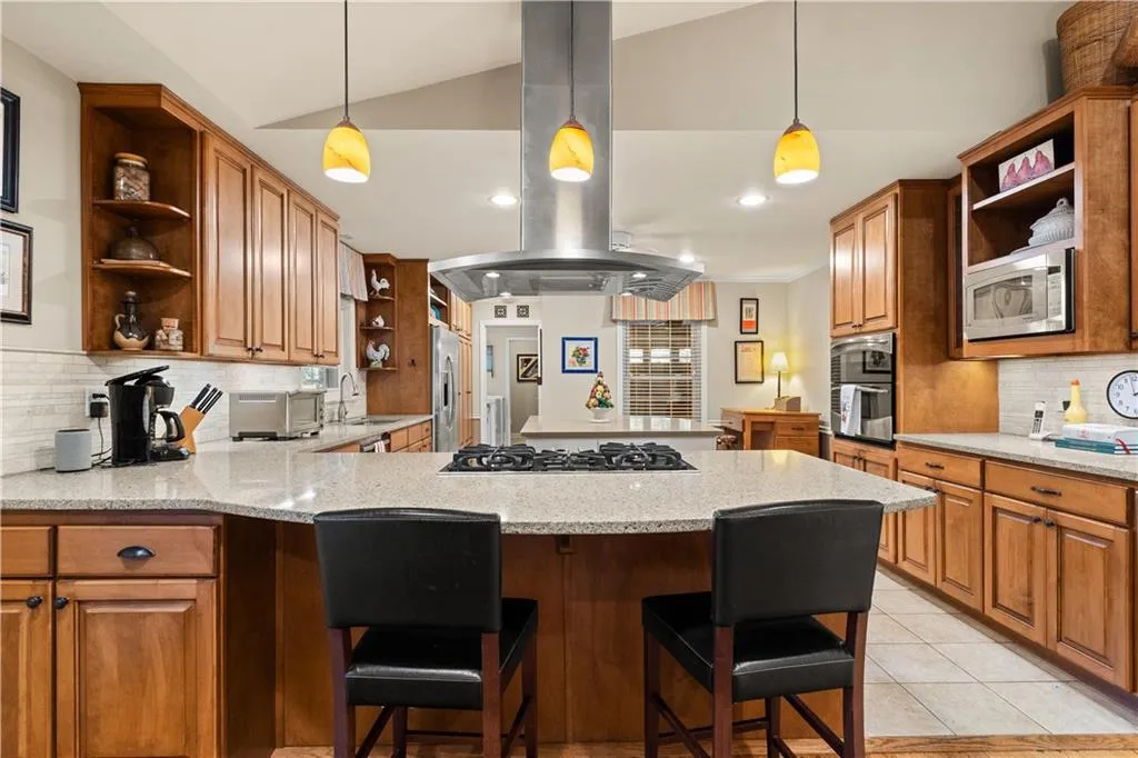 Kitchen with decorative backsplash, open shelves, island range hood, light stone counters, and recessed lighting