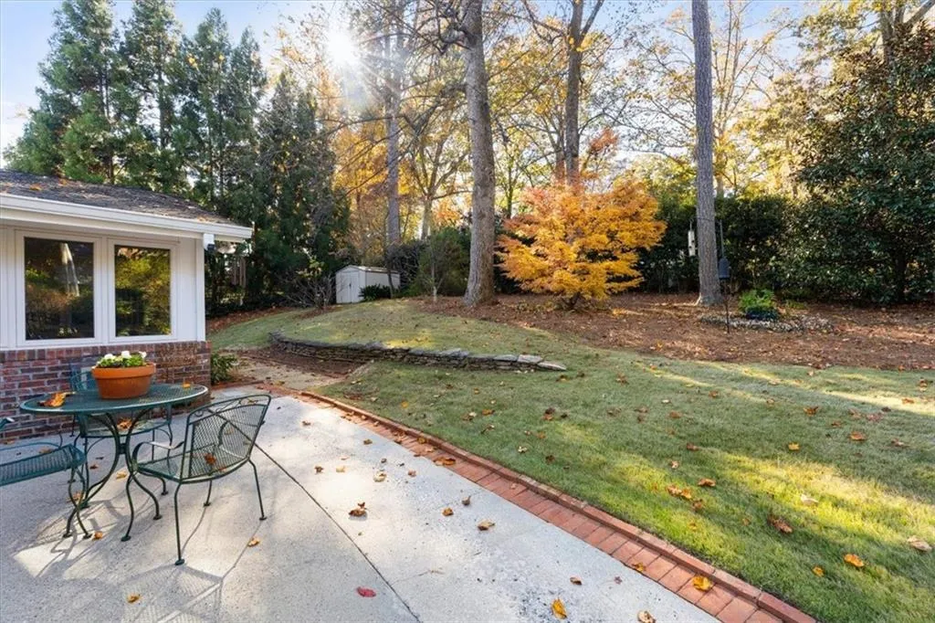 View of patio with a storage unit and view of wooded area