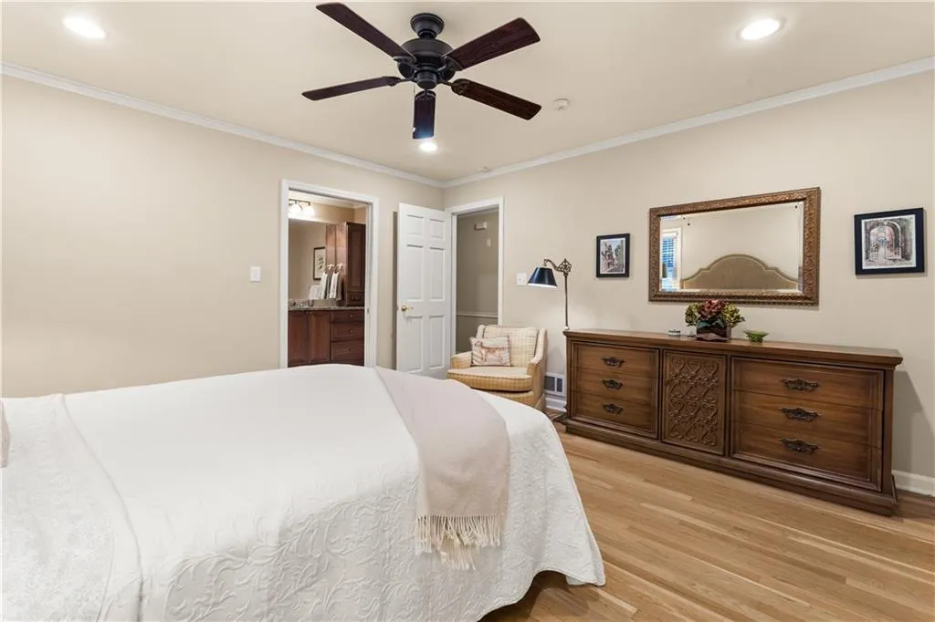 Bedroom featuring ornamental molding, light wood-style flooring, ceiling fan, recessed lighting, and ensuite bathroom