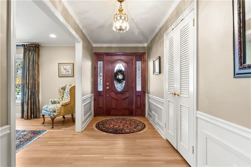 Foyer entrance featuring a chandelier, ornamental molding, light wood-type flooring, a decorative wall, and recessed lighting
