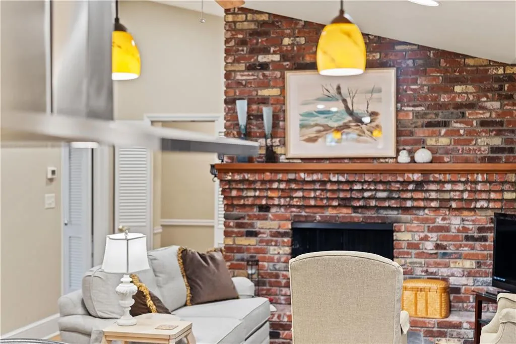 Living room featuring lofted ceiling, a brick fireplace, and brick wall