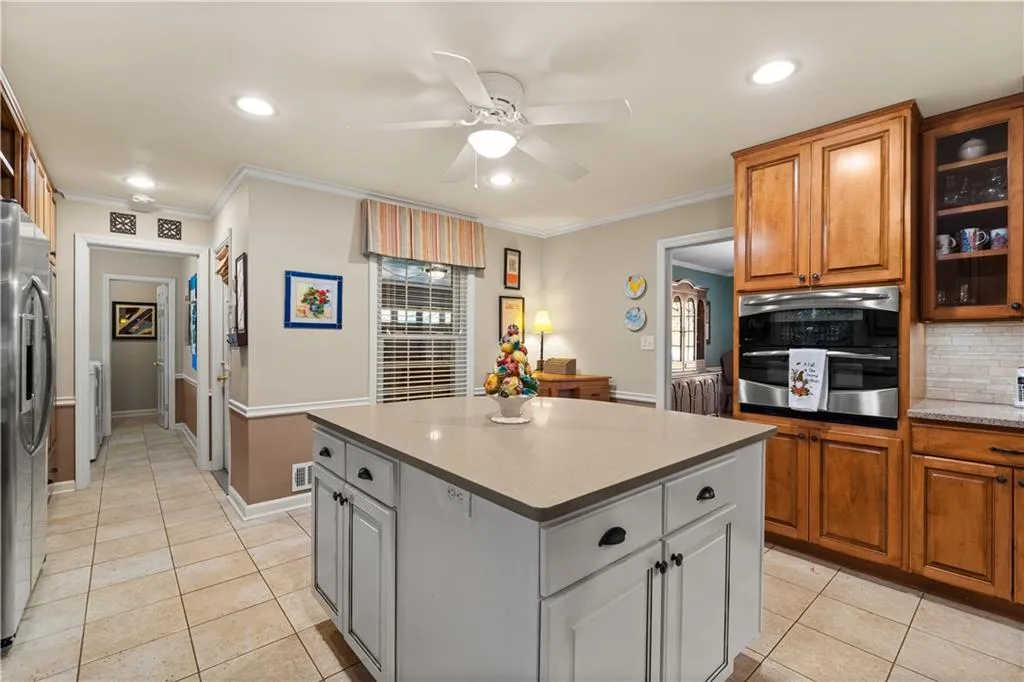 Kitchen featuring appliances with stainless steel finishes, decorative backsplash, light tile patterned floors, ornamental molding, and glass insert cabinets