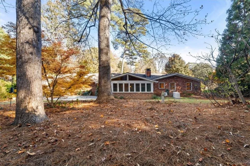 Back of property featuring a sunroom, a chimney, and brick siding