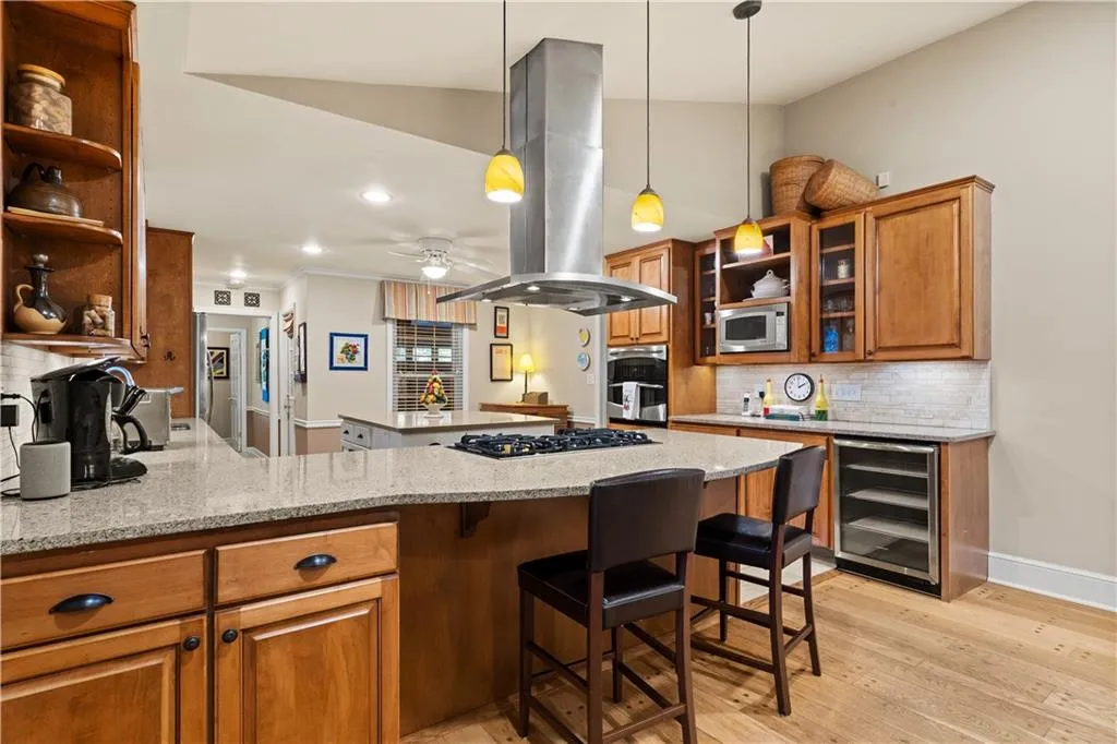 Kitchen with open shelves, decorative backsplash, brown cabinets, light stone counters, and recessed lighting