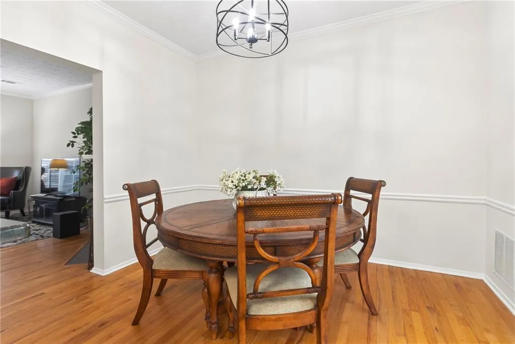 Dining area with ornamental molding, hanging lights, and wood finished floors