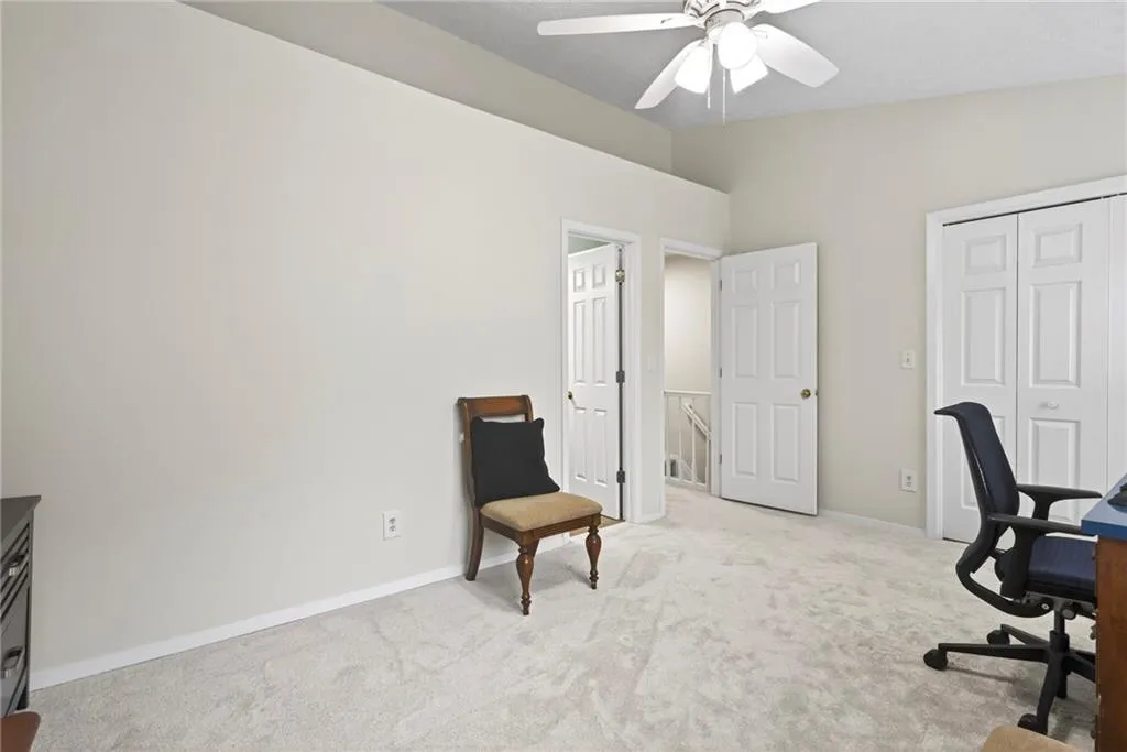 Home office with light colored carpet, vaulted ceiling, and ceiling fan