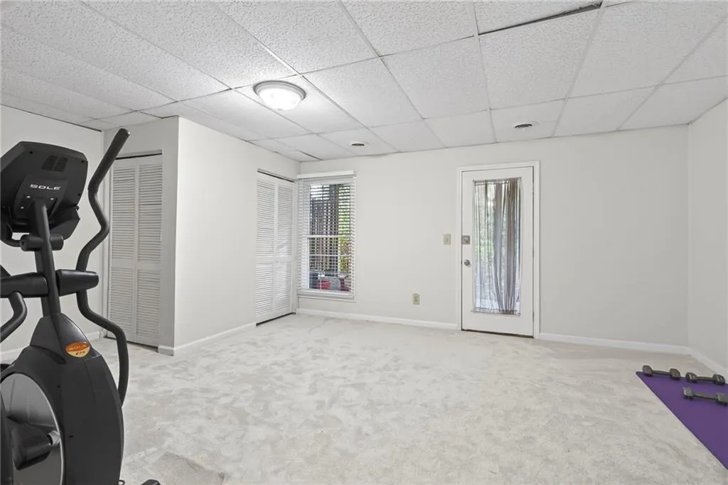 Workout room with light carpet and a paneled ceiling