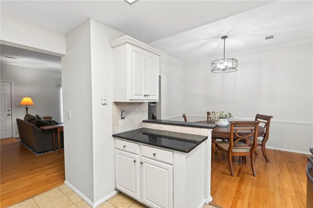 Kitchen featuring white cabinetry, ornamental molding, a textured ceiling, backsplash, and light wood-style floors