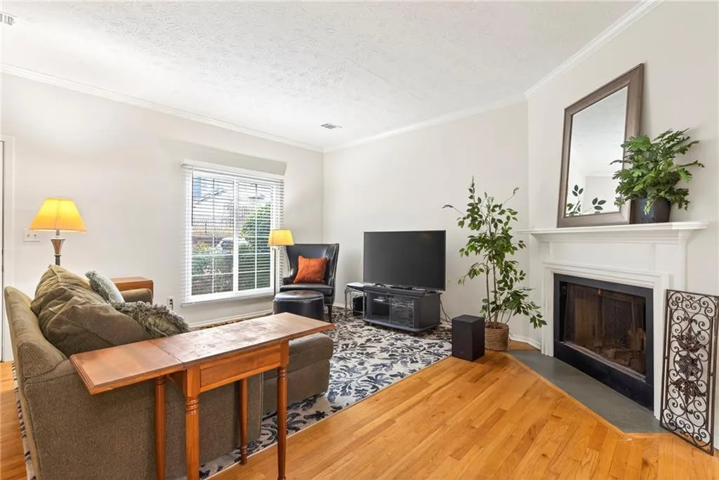 Living room with light wood-style floors, a textured ceiling, a fireplace with flush hearth, and crown molding