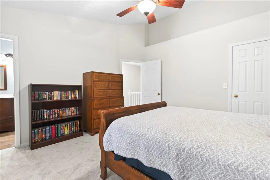 Bedroom with light carpet, a ceiling fan, a high ceiling, and ensuite bathroom