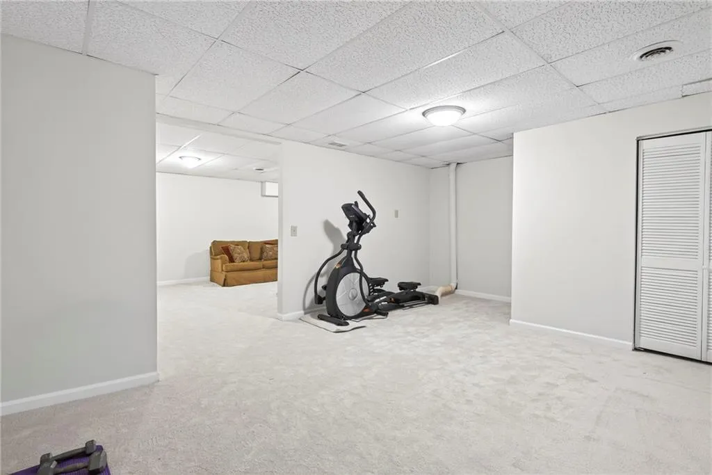 Exercise room featuring a drop ceiling and light carpet