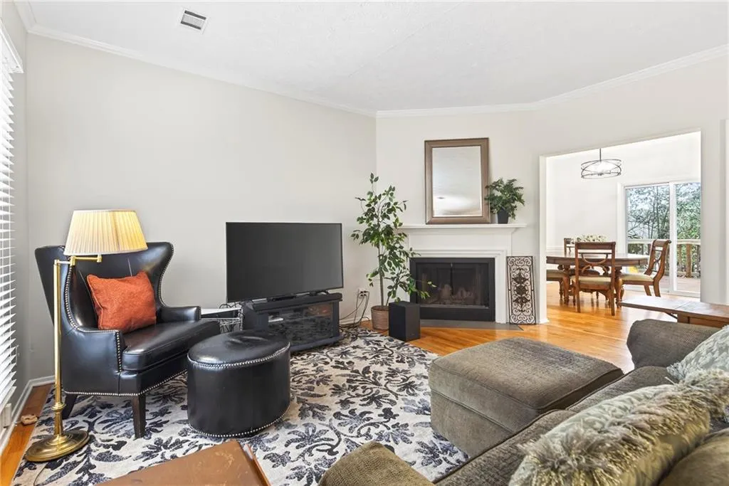 Living room featuring wood finished floors, ornamental molding, and a fireplace with flush hearth