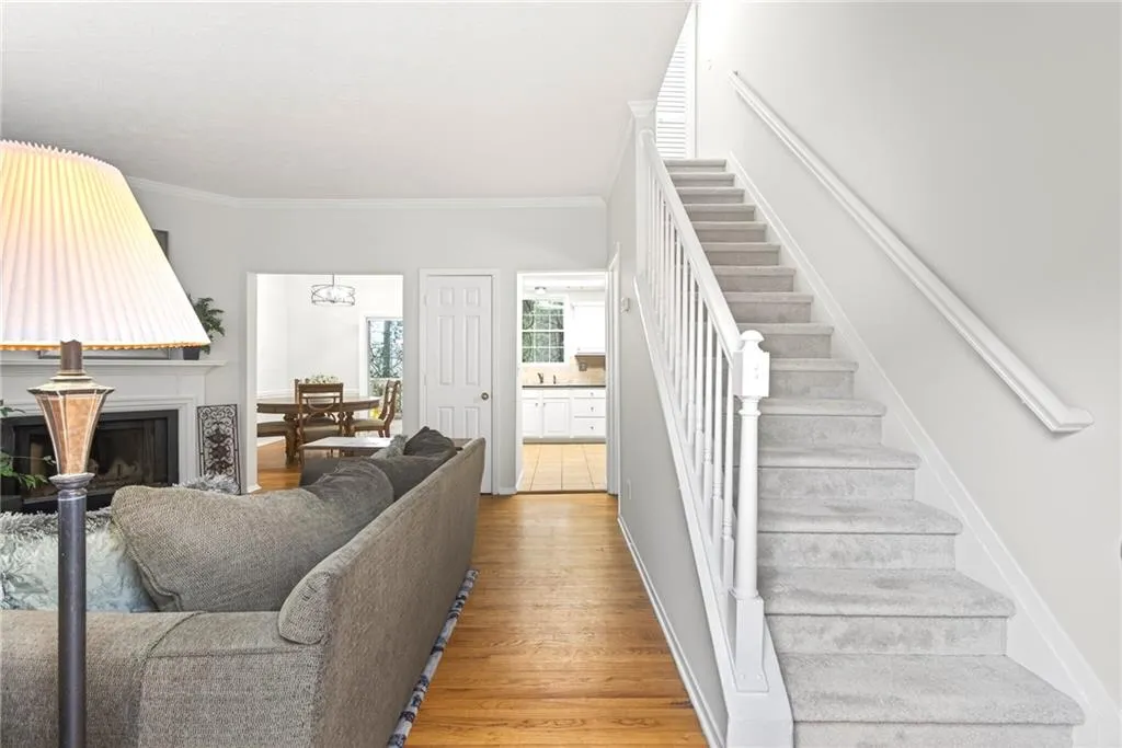 Stairs with wood finished floors, ornamental molding, and a fireplace