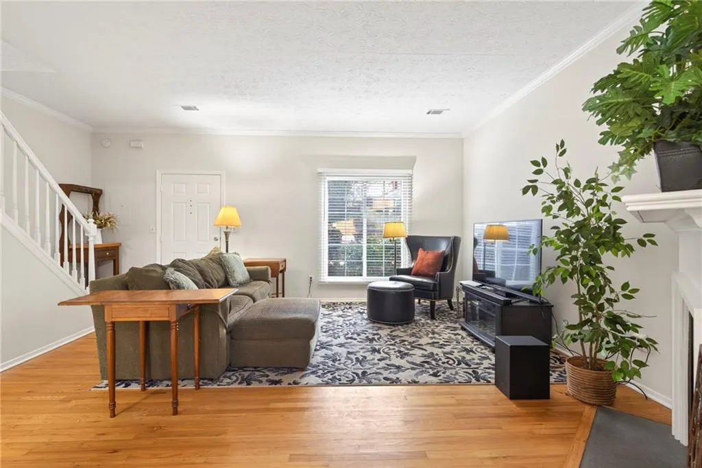 Living area featuring wood-type flooring, crown molding, a textured ceiling, and a fireplace with flush hearth