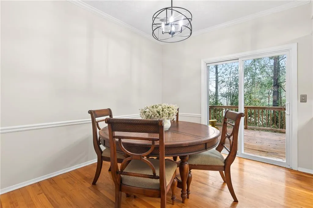 Dining room with light wood-type flooring, suspended lighting, and crown molding