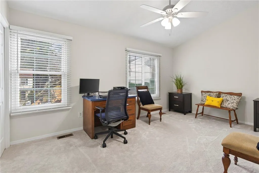 Home office with light colored carpet, vaulted ceiling, and a ceiling fan