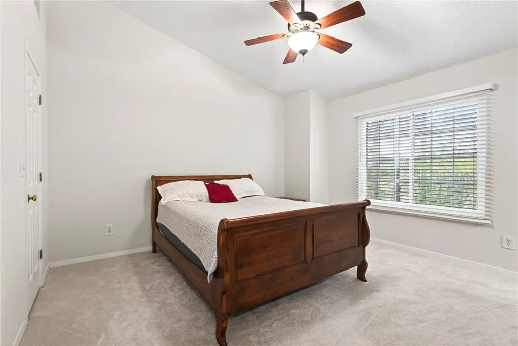 Bedroom with lofted ceiling, ceiling fan, and carpet