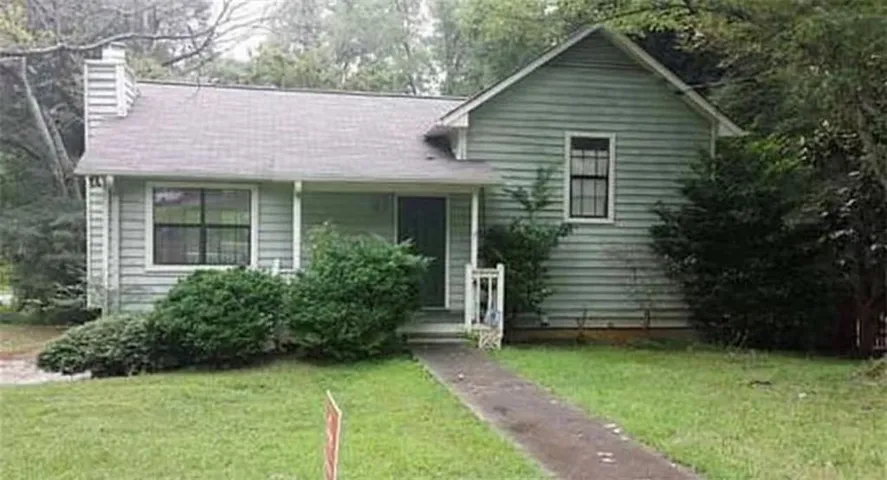 Split level home featuring a front yard, a chimney, and covered porch