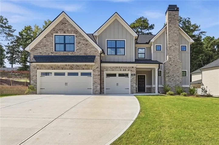 Brick and siding exterior with multiple gables, a prominent brick chimney, two-car garage, and a concrete driveway