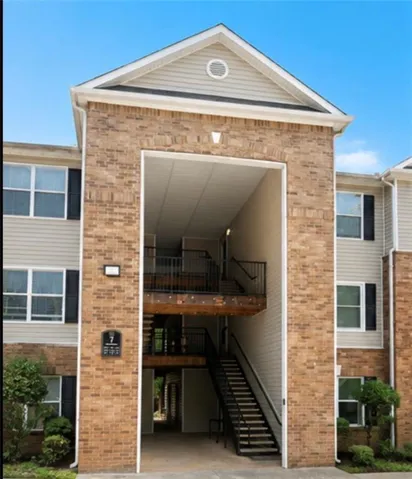 Multi-story building featuring brick and siding exterior, gabled roofline, multiple windows with dark shutters, and exterior metal staircases