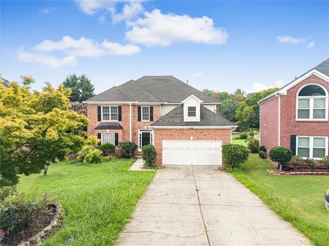 Two-story brick exterior with a dormer window, an attached two-car garage, and a concrete driveway