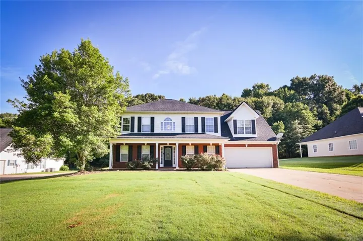 Two-story residence featuring a brick and white siding exterior, a covered front porch with white columns, and a dark shingled roof