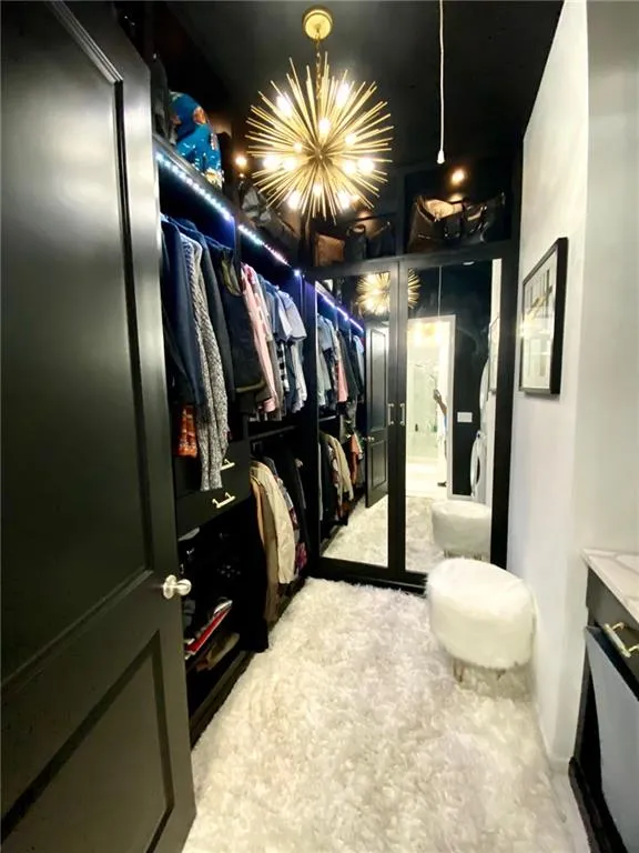 Walk in custom closet featuring an inviting chandelier