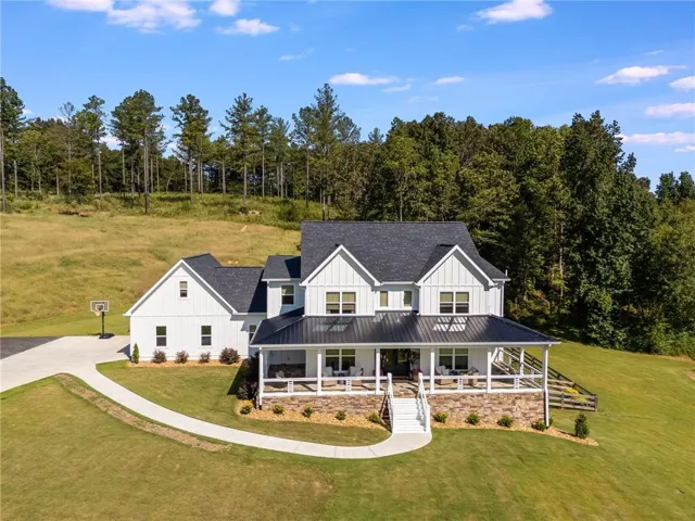 Modern farmhouse featuring covered porch, roof with shingles, a front lawn, board and batten siding, and a standing seam roof