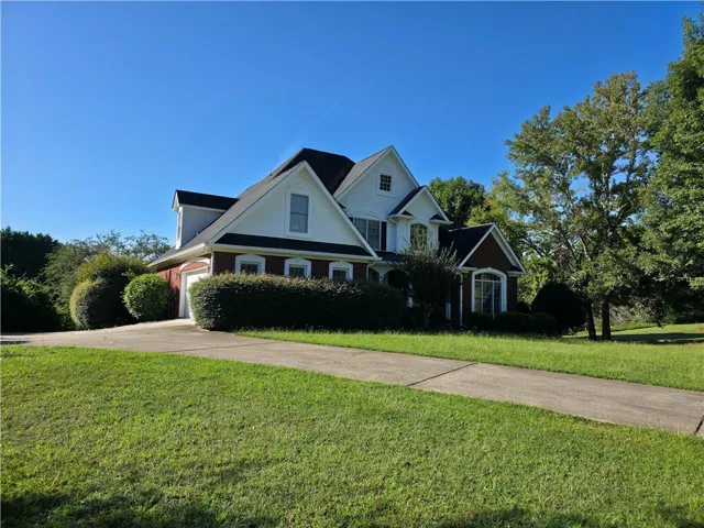 Two-story residence featuring a brick and white siding facade, a dark shingle roof, and an attached two-car garage