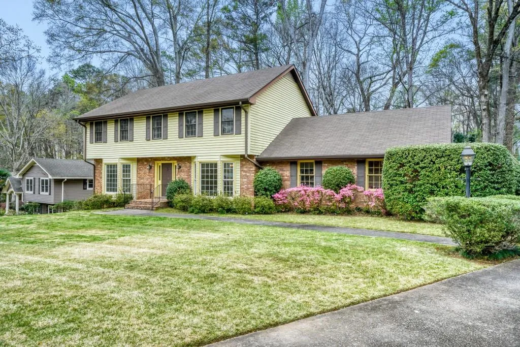 Colonial house featuring brick siding, a front yard, and roof with shingles