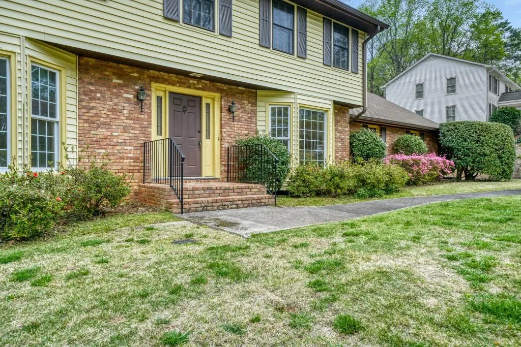 Doorway to property with a lawn and brick siding