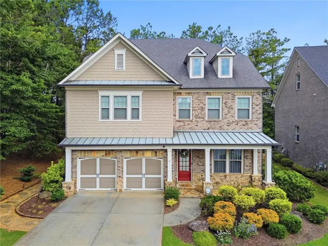 Two-story residence featuring a brick and shake exterior with a covered porch