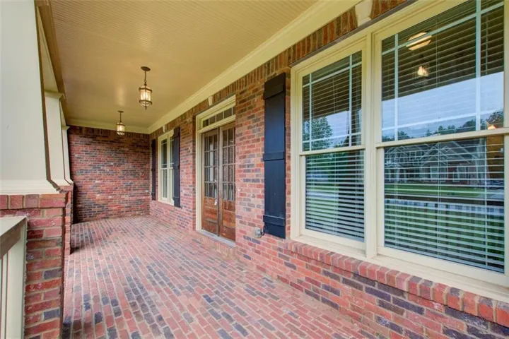 Brick front porch featuring brick flooring, white support columns, and an exterior brick wall