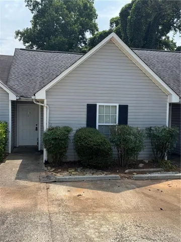Gray siding exterior with contrasting dark window shutters, an asphalt shingle roof, and a front entry door