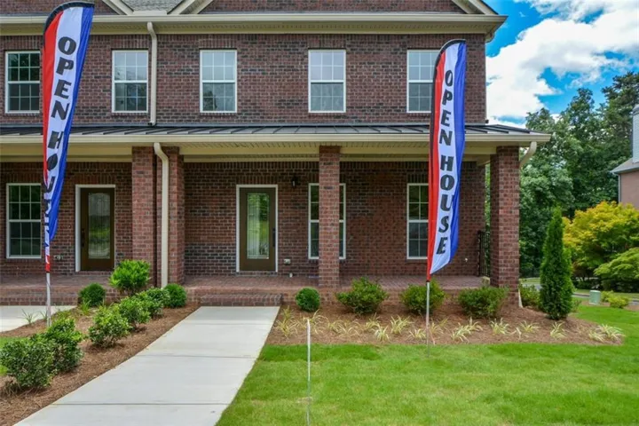 Brick facade structure with multiple windows, a covered entry porch, and a concrete walkway