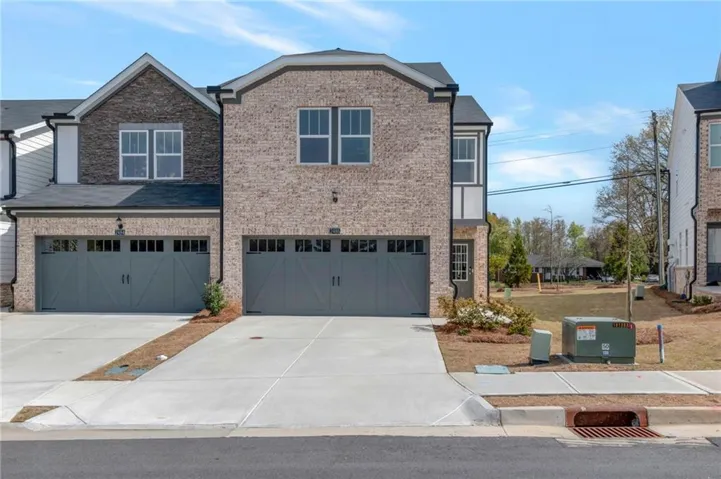 View of front of property featuring an attached garage, brick siding, and driveway