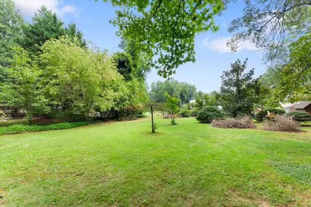 Expansive grassy lawn surrounded by mature trees and varied foliage