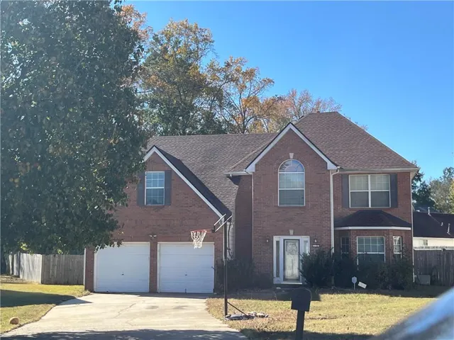 Colonial-style house featuring brick siding, concrete driveway, roof with shingles, and an attached garage