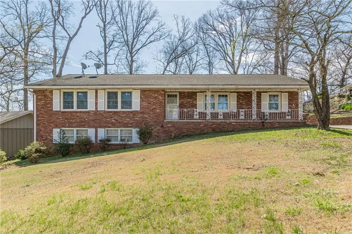 Brick facade residence featuring a covered front porch with white railings, and white window shutters