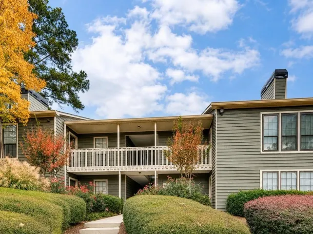 Two-story multi-unit dwelling with horizontal siding, featuring upper and lower level balconies with white railings