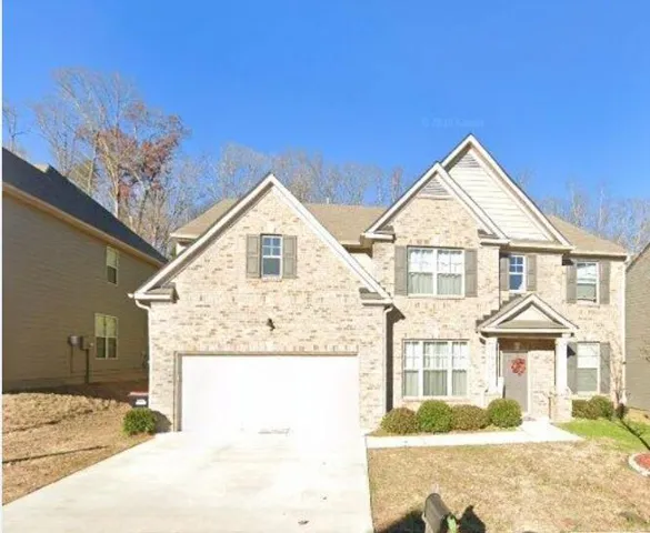 Elegant two-story stone exterior featuring a peaked roofline, multi-pane windows, and a two-car garage