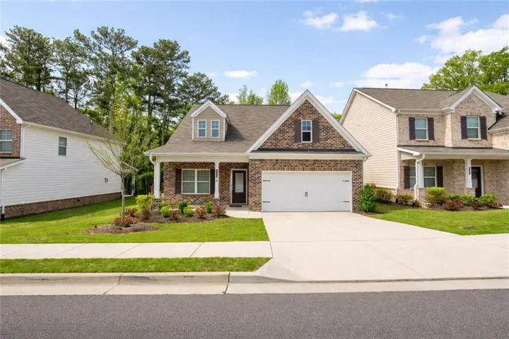 Craftsman-style home with covered porch, a front yard, driveway, brick siding, and a shingled roof