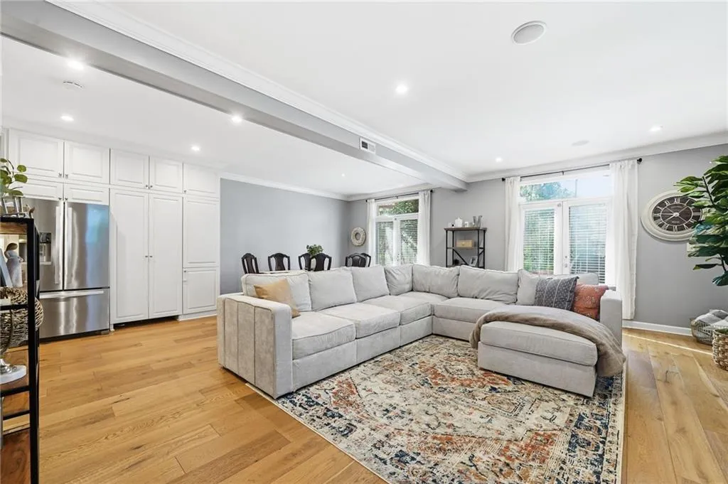 Living area with beamed ceiling, ornamental molding, light wood-style floors, and recessed lighting