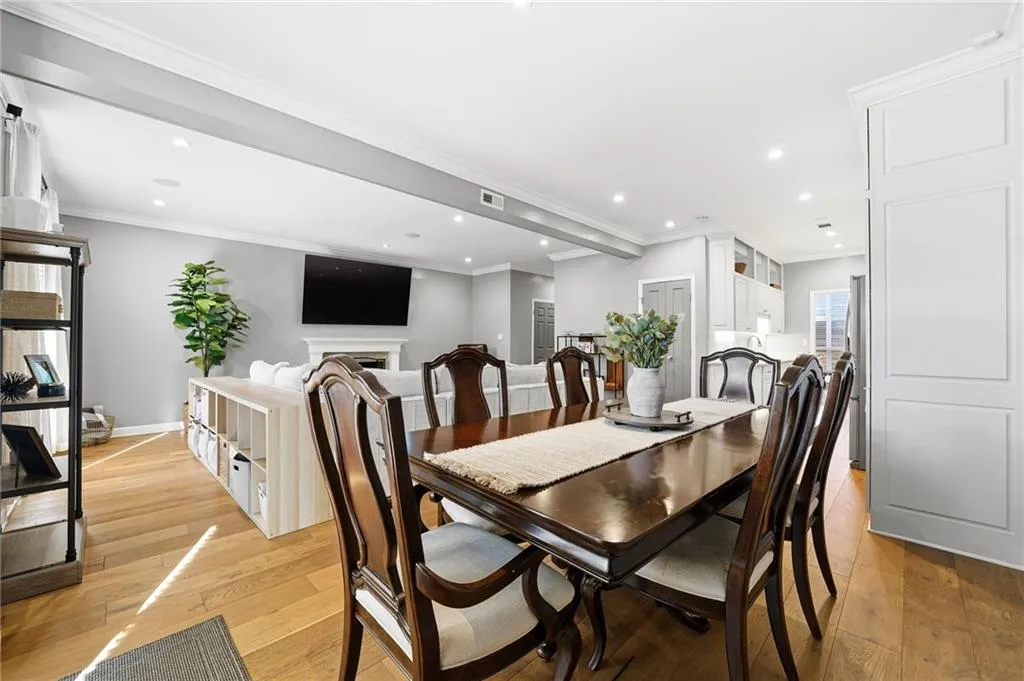 Dining space featuring light wood finished floors, crown molding, recessed lighting, and a fireplace