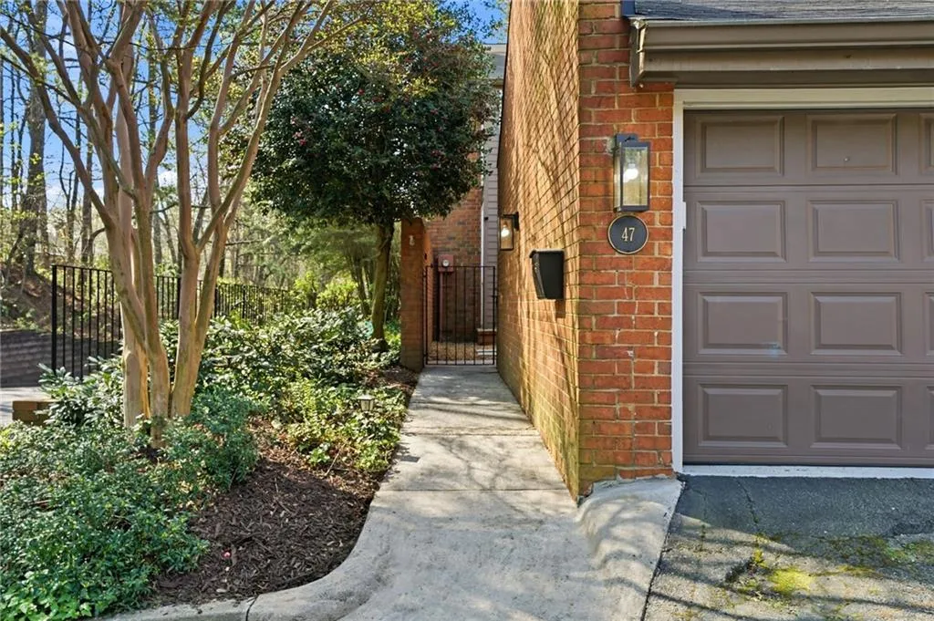 Property entrance featuring brick siding, a shingled roof, a garage, and a gate