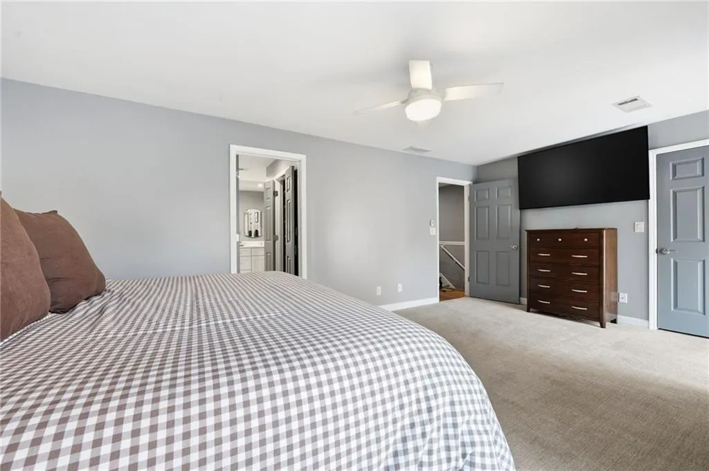 Bedroom featuring a ceiling fan, carpet, and ensuite bathroom
