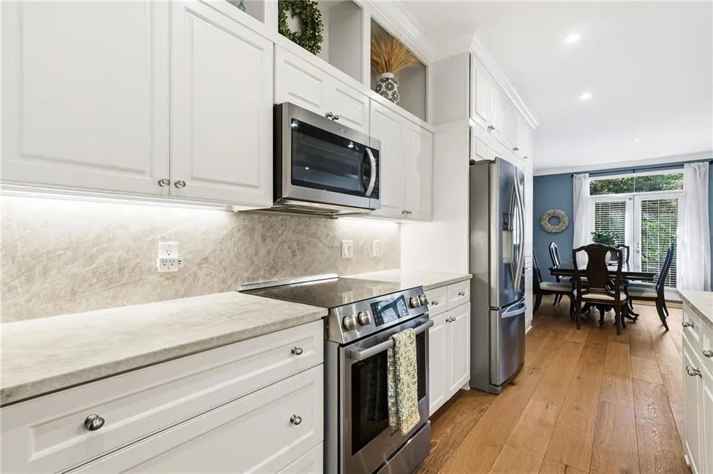 Kitchen featuring white cabinetry, stainless steel appliances, crown molding, light wood finished floors, and recessed lighting